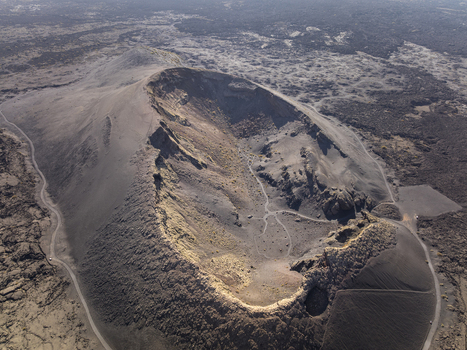 Aerial view of the dramatic volcanic crater with dark rugged terrain and winding paths in Lanzarote Canarias Spain. Aerial view of the dramatic volcanic crater with dark rugged terrain and winding paths in Lanzarote Canarias Spain.