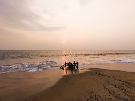Aerial view of fishermen with a traditional boat on a sandy beach during sunset in Galle Southern Province Sri Lanka.
