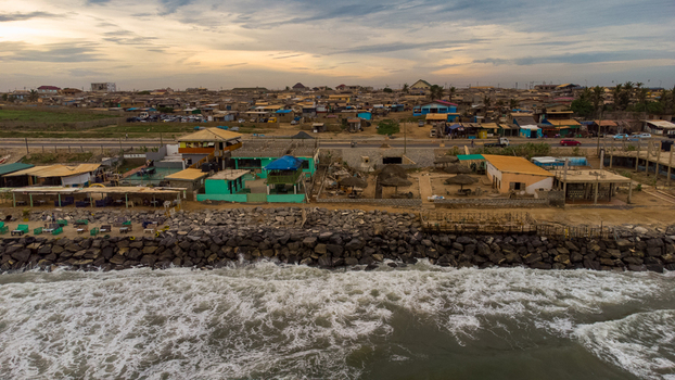 Aerial view of the Accra Tema Beach Road coastline featuring a rocky breakwater coastal buildings and waves crashing against the shore Accra Greater Accra Region Ghana.