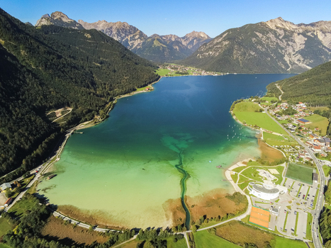 Aerial view of Achen Lake surrounded by lush green mountains and small villages in the Schwaz District Tyrol Austria.