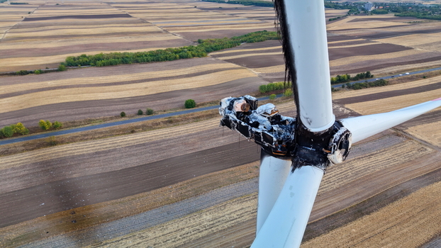 Aerial view of a burnt and damaged wind turbine with charred blades and nacelle standing in the middle of vast agricultural fields in Vladimirovac Vojvodina Serbia.