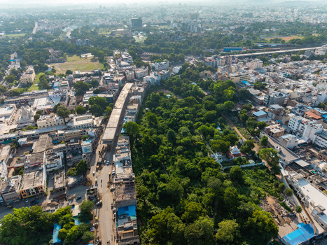 Aerial view of the dense urban landscape of Udaipur featuring a large green park area surrounded by residential buildings and roads in Udaipur Rajasthan India.