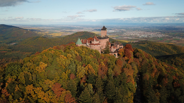 Aerial view of the historic Chateau du Haut Koenigsbourg nestled amidst vibrant autumn forests on a mountain ridge in Orschwiller Grand Est France.