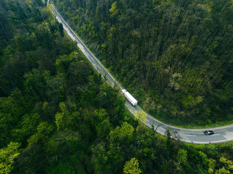 Aerial view of a truck and car navigating a winding road snaking through dense forest creating a striking contrast between nature and transport Novi Sad Vojvodina Serbia. Aerial view of a truck and car navigating a winding road snaking through dense forest creating a striking contrast between nature and transport Novi Sad Vojvodina Serbia.