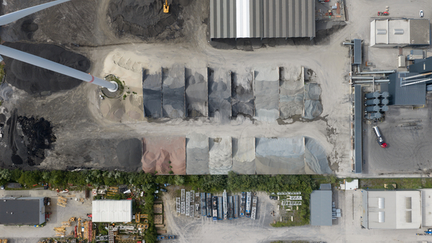 Aerial view of the industrial site at Feluy de Parc Industriel with various piles of gravel and aggregates industrial buildings and a wind turbine base in Seneffe Region wallonne Belgium.