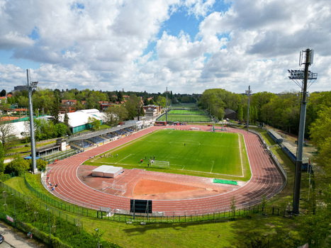 Aerial view of a sports stadium with a green grass pitch and red running track surrounded by trees and floodlights in Woluwe Saint Lambert Bruxelles Belgium. Aerial view of a sports stadium with a green grass pitch and red running track surrounded by trees and floodlights in Woluwe Saint Lambert Bruxelles Belgium.