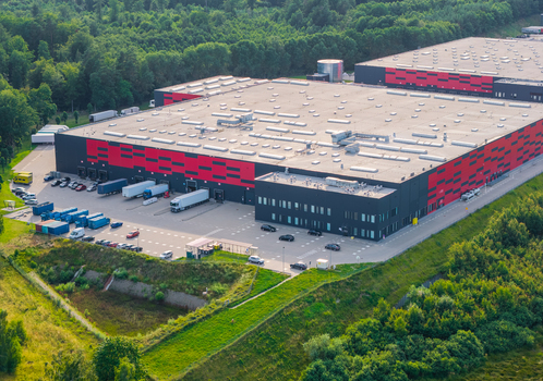 Aerial view of the Gdansk Kowale Distribution Centre a large industrial facility with red and black facade loading docks and parked trucks in Kowale Pomeranian Voivodeship Poland. Aerial view of the Gdansk Kowale Distribution Centre a large industrial facility with red and black facade loading docks and parked trucks in Kowale Pomeranian Voivodeship Poland.