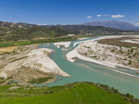 Aerial view of the Vjosa Wild River National Park featuring turquoise river channels expansive white sandbanks and lush green hills in Permet Gjirokaster County Albania. Aerial view of the Vjosa Wild River National Park featuring turquoise river channels expansive white sandbanks and lush green hills in Permet Gjirokaster County Albania.