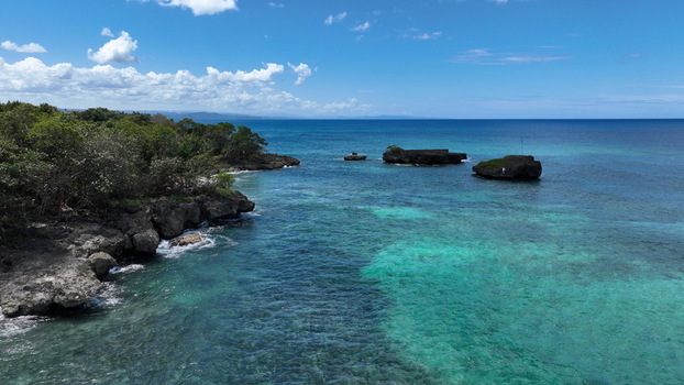 Aerial view of the turquoise Caribbean Sea along the rocky coastline with lush green vegetation and small rock islands in Rio San Juan Maria Trinidad Sanchez Dominican Republic. Aerial view of the turquoise Caribbean Sea along the rocky coastline with lush green vegetation and small rock islands in Rio San Juan Maria Trinidad Sanchez Dominican Republic.
