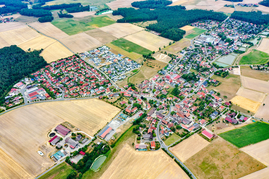 Aerial view of the village of Oberreichenbach featuring residential houses with red roofs surrounded by vast agricultural fields and green forests Oberreichenbach Bavaria Germany. Aerial view of the village of Oberreichenbach featuring residential houses with red roofs surrounded by vast agricultural fields and green forests Oberreichenbach Bavaria Germany.