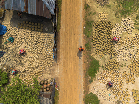 Joypurhat Rajshahi Division Bangladesh 28 September 2026 Aerial view of workers arranging clay pots to dry on the ground along a dirt road in a rural village. Joypurhat Rajshahi Division Bangladesh 28 September 2026 Aerial view of workers arranging clay pots to dry on the ground along a dirt road in a rural village.