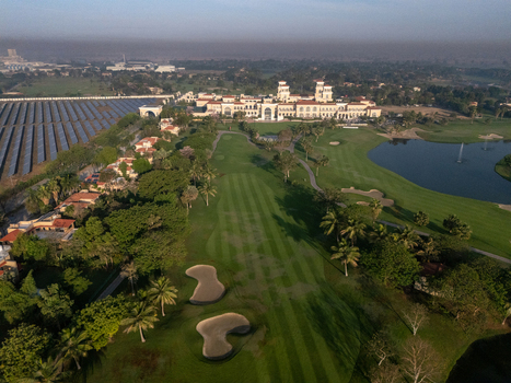 Ahmedabad India 21 March 2026 Aerial view of Kalhaar Blues Greens Golf Club featuring lush green fairways sand bunkers a large lake and adjacent solar panel arrays.