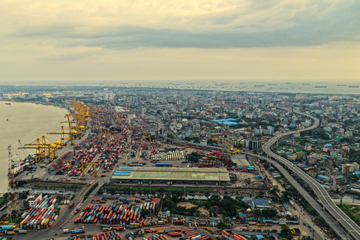 Aerial view of Chattogram Port with numerous shipping containers industrial cranes and the surrounding urban skyline along the coast in Chittagong Chittagong Division Bangladesh.