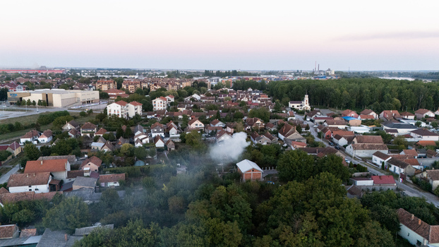 Aerial view of the residential area of Sremska Mitrovica with houses lush trees and a plume of smoke rising from a garden in Sremska Mitrovica Vojvodina Serbia. Aerial view of the residential area of Sremska Mitrovica with houses lush trees and a plume of smoke rising from a garden in Sremska Mitrovica Vojvodina Serbia.