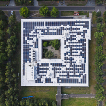 Aerial view of HTC 33 Design building featuring a large rooftop solar panel array and a central green courtyard surrounded by trees in Eindhoven Noord Brabant Netherlands. Aerial view of HTC 33 Design building featuring a large rooftop solar panel array and a central green courtyard surrounded by trees in Eindhoven Noord Brabant Netherlands.