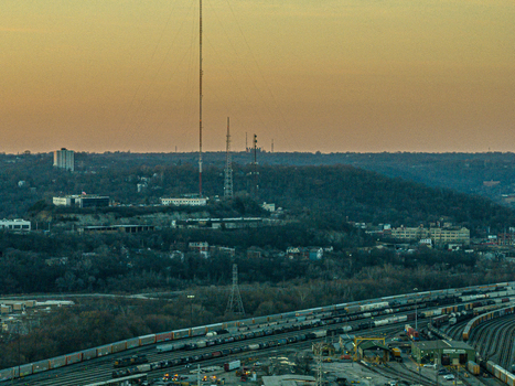 Cincinnati United States 27 February 2026 Aerial view of a train yard nestled amidst a dense forest under a warm golden sky with tall communication towers piercing the horizon. Cincinnati United States 27 February 2026 Aerial view of a train yard nestled amidst a dense forest under a warm golden sky with tall communication towers piercing the horizon.