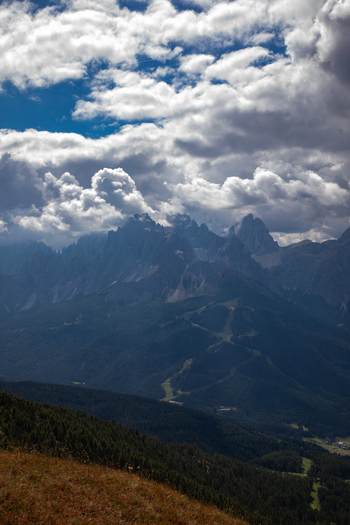 Aerial view of the Dolomites mountain range with dramatic clouds over rocky peaks and forested slopes in Rocca Pietore Veneto Italy.