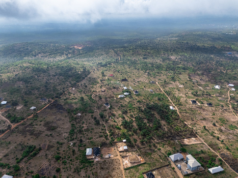 Aerial view of scattered homes amidst a tapestry of dry brown earth and sparse green vegetation under a brooding sky Elu Abia Nigeria. Aerial view of scattered homes amidst a tapestry of dry brown earth and sparse green vegetation under a brooding sky Elu Abia Nigeria.