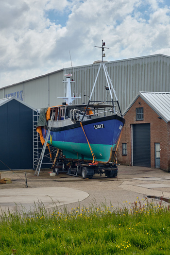 Den Oever Netherlands 18 May 2026 View of the Vissershaven fishing boat on a trailer for maintenance with harbor buildings and a cloudy sky. Den Oever Netherlands 18 May 2026 View of the Vissershaven fishing boat on a trailer for maintenance with harbor buildings and a cloudy sky.