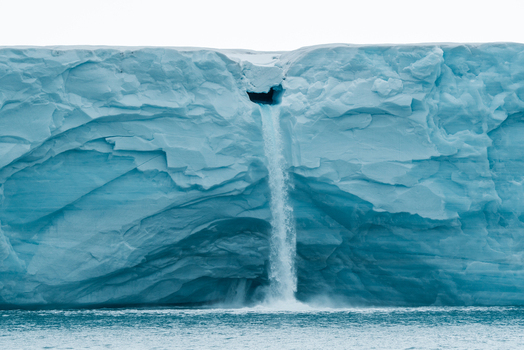 Svalbard and Jan Mayen 26 July 2025 View of a waterfall cascading from a massive blue glacier wall into the Arctic Ocean. Svalbard and Jan Mayen 26 July 2025 View of a waterfall cascading from a massive blue glacier wall into the Arctic Ocean.