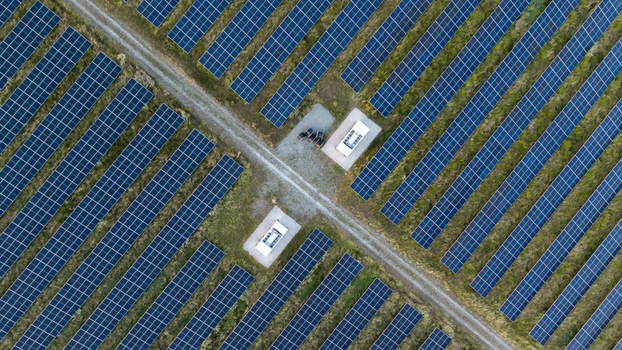 Aerial view of a large solar farm with rows of photovoltaic panels arranged in a grid pattern separated by gravel paths and small electrical substations in Poland. Aerial view of a large solar farm with rows of photovoltaic panels arranged in a grid pattern separated by gravel paths and small electrical substations in Poland.