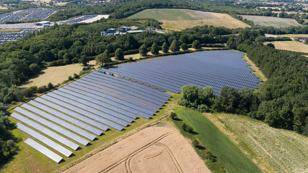 Aerial view of a large solar farm with rows of photovoltaic panels situated in a rural landscape surrounded by green trees and fields in Atherstone England United Kingdom. Aerial view of a large solar farm with rows of photovoltaic panels situated in a rural landscape surrounded by green trees and fields in Atherstone England United Kingdom.