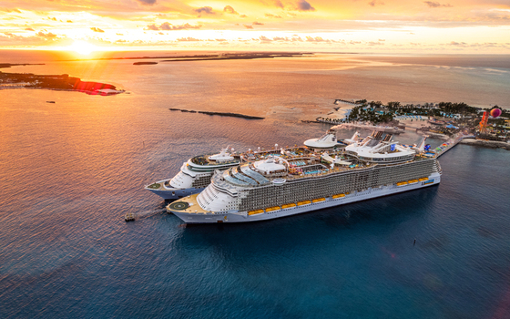 The Bahamas 04 November 2021 Aerial view of cruise ships docked at CocoCay in The Bahamas during a vibrant golden hour sunset with calm turquoise waters and the island s infrastructure visible.