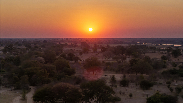 Aerial view of the Okavango Delta at sunset featuring vast plains scattered trees and a golden horizon in Okavango Delta North West District Botswana. Aerial view of the Okavango Delta at sunset featuring vast plains scattered trees and a golden horizon in Okavango Delta North West District Botswana.