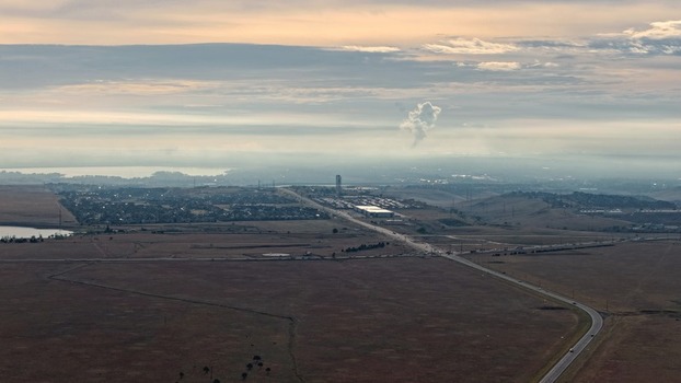 Aerial view of the landscape near Golden with a highway stretching through the plains suburban buildings and a distant plume of smoke in Golden Colorado United States.