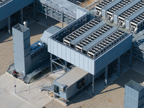 Aerial view of a modern datacenter featuring large industrial cooling units and ventilation systems on the roof set against a clean paved ground area in The Netherlands. Aerial view of a modern datacenter featuring large industrial cooling units and ventilation systems on the roof set against a clean paved ground area in The Netherlands.