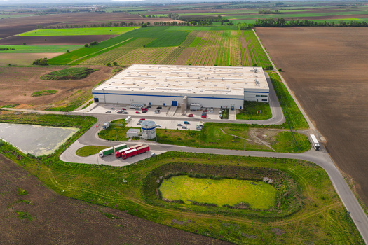 Aerial view of a large industrial warehouse building surrounded by green fields and agricultural land in Hrusky South Moravian Region Czechia. Aerial view of a large industrial warehouse building surrounded by green fields and agricultural land in Hrusky South Moravian Region Czechia.
