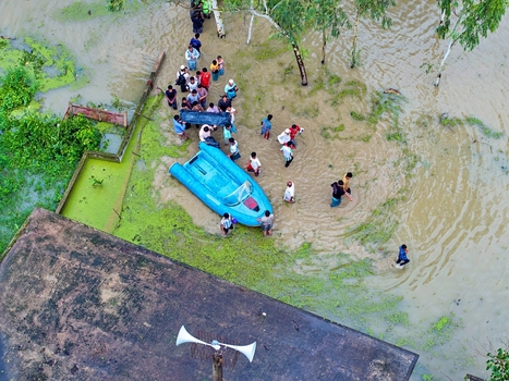 Banshkhali Upazila Chittagong Division Bangladesh 10 July 2026 Aerial view of people wading through floodwaters and gathered around a blue boat in a submerged area. Banshkhali Upazila Chittagong Division Bangladesh 10 July 2026 Aerial view of people wading through floodwaters and gathered around a blue boat in a submerged area.