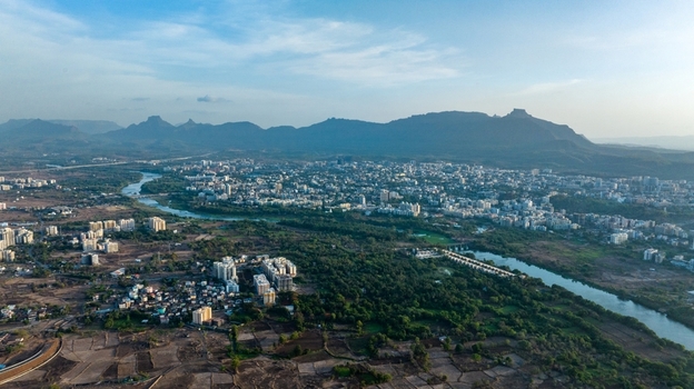 Aerial view of the urban landscape of Badlapur with a winding river residential buildings and distant mountains under a clear sky in Badlapur Maharashtra India. Aerial view of the urban landscape of Badlapur with a winding river residential buildings and distant mountains under a clear sky in Badlapur Maharashtra India.