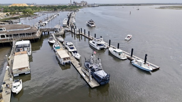 Aerial view of a marina full of boats on dark water a building and distant industrial facility Fernandina Beach Florida United States. Aerial view of a marina full of boats on dark water a building and distant industrial facility Fernandina Beach Florida United States.