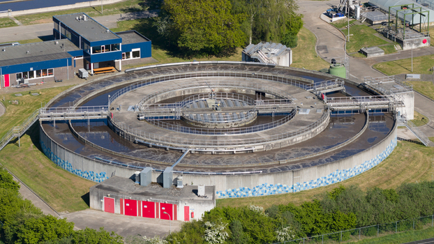 Aerial view of the RWZI Echten wastewater treatment plant featuring a large circular clarifier tank and industrial buildings in Hoogeveen Drenthe Netherlands. Aerial view of the RWZI Echten wastewater treatment plant featuring a large circular clarifier tank and industrial buildings in Hoogeveen Drenthe Netherlands.
