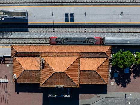 Aerial view of the train station in Evora with its distinctive red tiled roof adjacent railway tracks with a train and surrounding platform areas in Evora Evora District Portugal. Aerial view of the train station in Evora with its distinctive red tiled roof adjacent railway tracks with a train and surrounding platform areas in Evora Evora District Portugal.