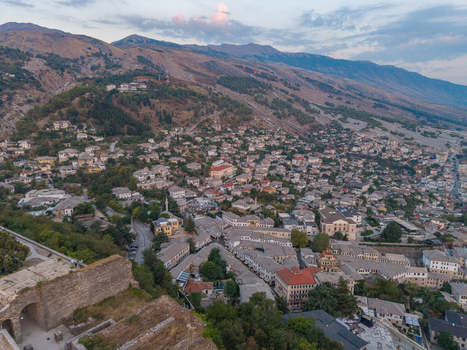Aerial view of the historic stone city with its traditional rooftops and castle walls nestled in the mountains of Gjirokaster Gjirokaster County Albania. Aerial view of the historic stone city with its traditional rooftops and castle walls nestled in the mountains of Gjirokaster Gjirokaster County Albania.