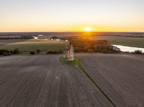 Aerial view of the historic Pusztatorony church ruins surrounded by vast agricultural fields and a winding river at sunset in Somogyvamos Hungary. Aerial view of the historic Pusztatorony church ruins surrounded by vast agricultural fields and a winding river at sunset in Somogyvamos Hungary.