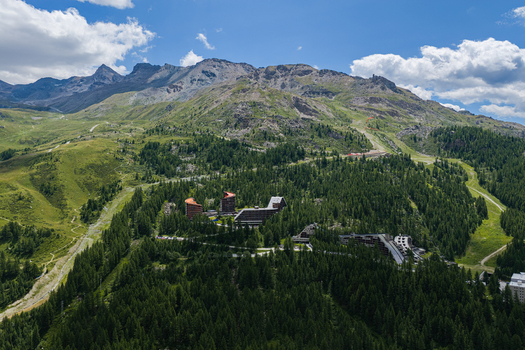 Aerial view of the mountain resort of Breuil Cervinia nestled in the pine forests with surrounding Alpine peaks under a blue sky in Breuil Cervinia Aosta Valley Italy. Aerial view of the mountain resort of Breuil Cervinia nestled in the pine forests with surrounding Alpine peaks under a blue sky in Breuil Cervinia Aosta Valley Italy.