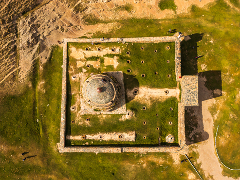 Aerial view of Tash Rabat Caravan Palace a historic stone caravanserai with a central dome surrounded by grassy mountain terrain in At Bashi District Naryn Region Kyrgyzstan. Aerial view of Tash Rabat Caravan Palace a historic stone caravanserai with a central dome surrounded by grassy mountain terrain in At Bashi District Naryn Region Kyrgyzstan.