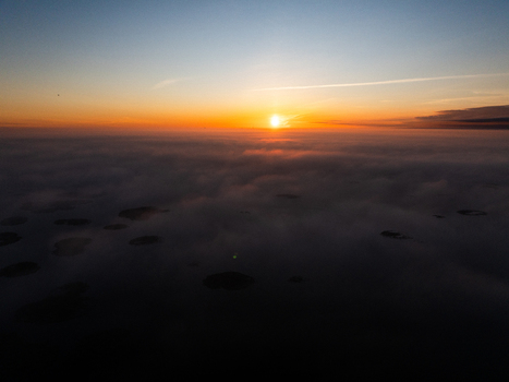 Aerial view of Babites ezers shrouded in thick morning fog during a vibrant sunrise in Marupes novads Latvia. Aerial view of Babites ezers shrouded in thick morning fog during a vibrant sunrise in Marupes novads Latvia.