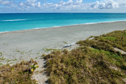 Aerial view of the shorelines where the Atlantic Ocean meets the sandy beach with beach chairs scattered in the sand Jupiter Island Florida United States.