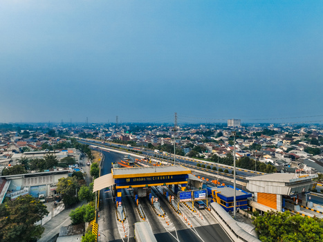 Aerial view of the Cikunir 4 toll gate with vehicles passing through lanes surrounded by urban residential areas and clear blue sky in Kecamatan Bekasi Selatan Jawa Barat Indonesia. Aerial view of the Cikunir 4 toll gate with vehicles passing through lanes surrounded by urban residential areas and clear blue sky in Kecamatan Bekasi Selatan Jawa Barat Indonesia.