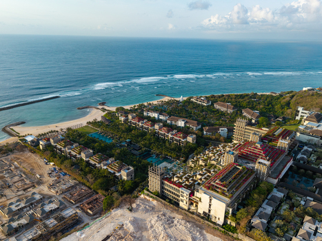 Aerial view of The Apurva Kempinski Bali resort with tiered architecture lush gardens and pools along the coastline with turquoise ocean waters. Kecamatan Kuta Selatan Bali Indonesia. Aerial view of The Apurva Kempinski Bali resort with tiered architecture lush gardens and pools along the coastline with turquoise ocean waters. Kecamatan Kuta Selatan Bali Indonesia.