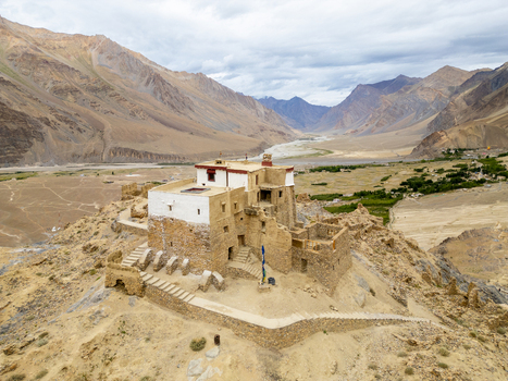 Aerial view of the historic Karsha Monastery perched on a rocky hillside overlooking the vast arid landscape and river valley in Zanskar Ladakh India.
