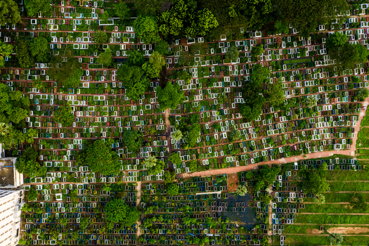 Aerial view of a dense cemetery with numerous graves arranged in rows interspersed with lush green trees and narrow pathways in Dhaka Dhaka Division Bangladesh.
