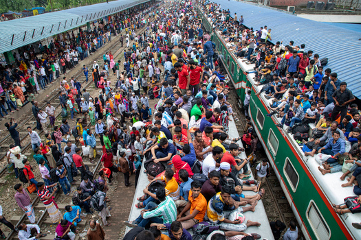 Dhaka Bangladesh 15 June 2018 View of a massive crowd of passengers sitting on the roofs of trains and standing on platforms at Airport Railway Station during a busy travel period. Dhaka Bangladesh 15 June 2018 View of a massive crowd of passengers sitting on the roofs of trains and standing on platforms at Airport Railway Station during a busy travel period.
