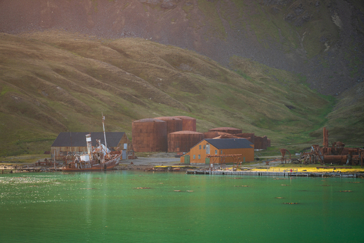 View of the historic Grytviken whaling station with rusted oil tanks abandoned buildings and a shipwreck near turquoise waters in Grytviken South Georgia and the South Sandwich Islands. View of the historic Grytviken whaling station with rusted oil tanks abandoned buildings and a shipwreck near turquoise waters in Grytviken South Georgia and the South Sandwich Islands.