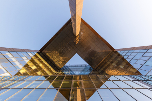 View of the geometric glass facade of a modern skyscraper reflecting the clear blue sky in London England United Kingdom.
