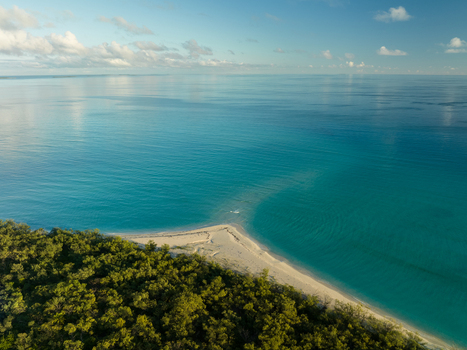 Aerial view of the meeting of lush green forest and pristine white sand beach with the turquoise sea Ouvéa Loyalty Islands Province New Caledonia. Aerial view of the meeting of lush green forest and pristine white sand beach with the turquoise sea Ouvéa Loyalty Islands Province New Caledonia.
